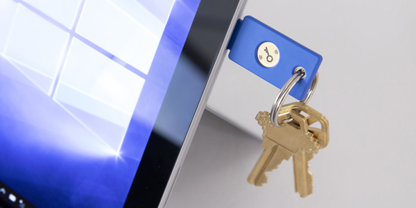 A blue Yubikey attached to a keychain, placed in a laptop's USB port